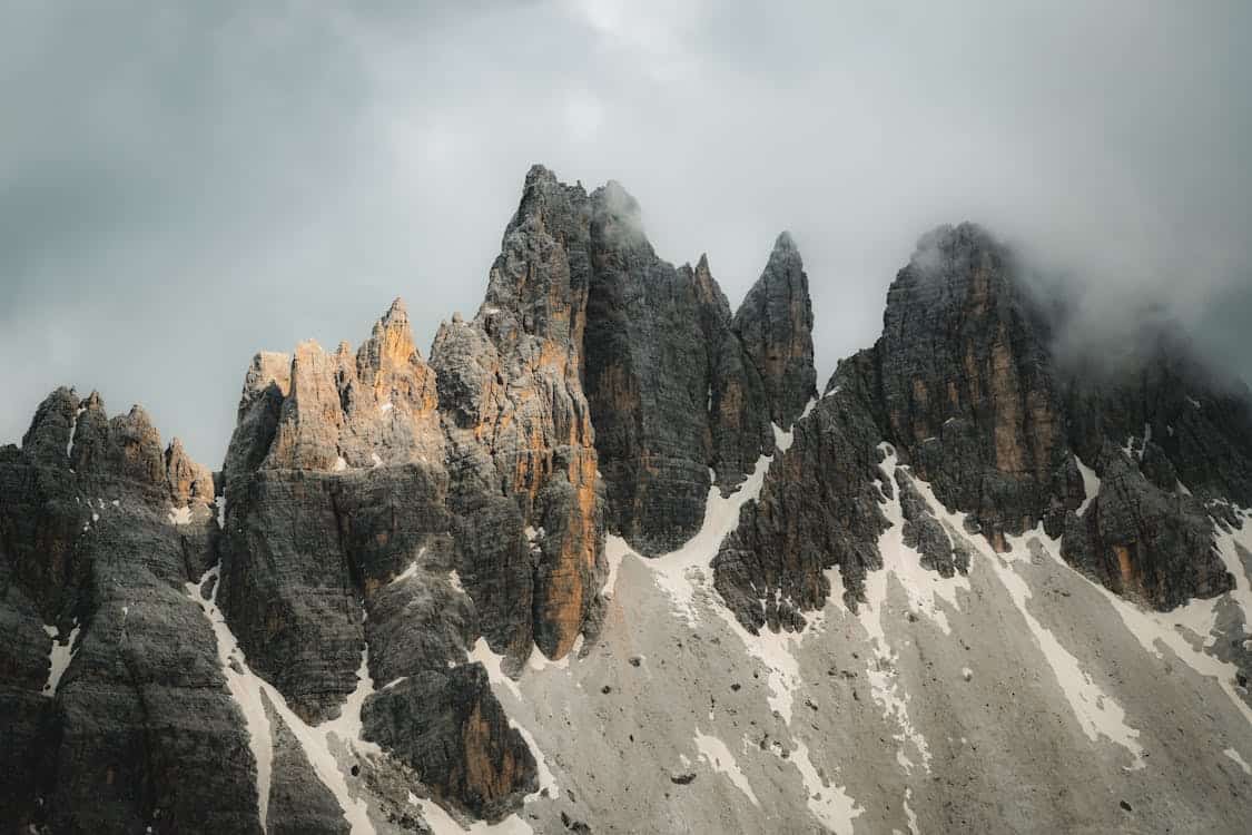 Montagnes rocheuses brumeuses avec sommets escarpés et neige.
