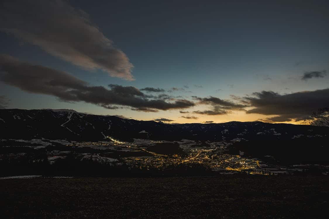 Vue panoramique de KAERUS Staging au crépuscule avec montagnes et ville illuminée.